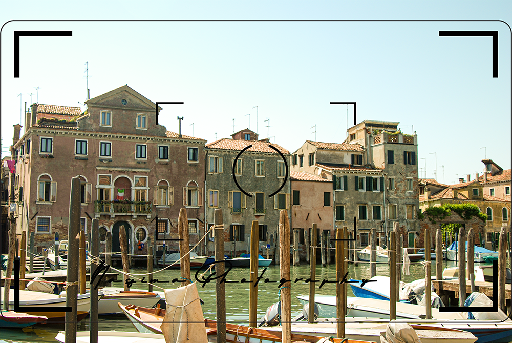 view from the channel over some boats and gondolas to houses in Venice