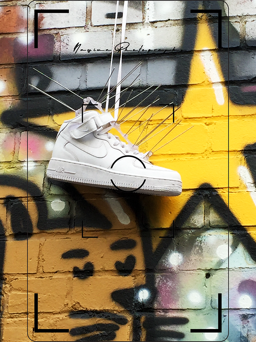 Weißer Sneaker mit Metallspitzen vor einer farbig besprühten Backsteinwand der Naxoshalle in Frankfurt am Main.