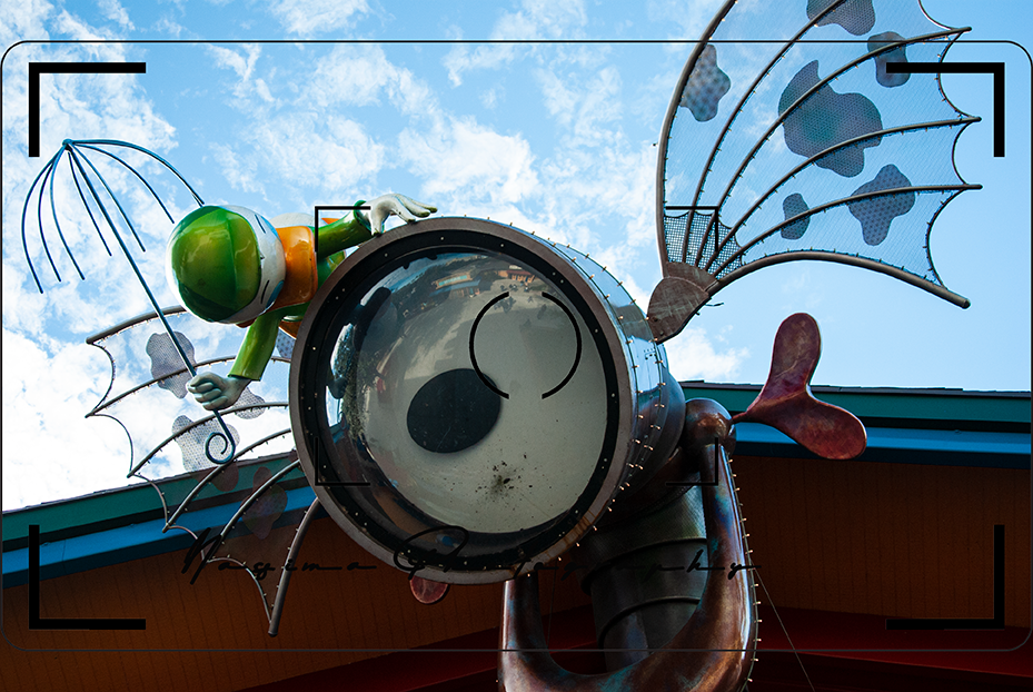 eye in a white circle, wings on the left and right and a small green figure looking down sitting on the white circle at Disney market place in orlando florida