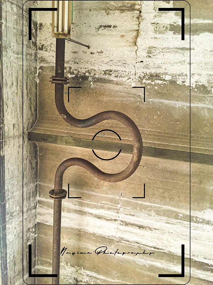 tube with a bend in a room with cement wall